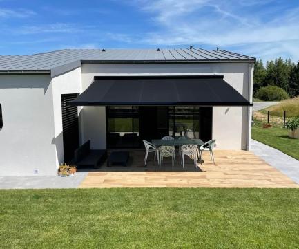 Store banne beige installé en façade avec éclairage LED, posé par l’équipe EnjoyHome sur une terrasse moderne
