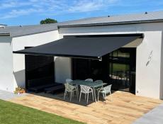 Store banne beige installé en façade avec éclairage LED, posé par l’équipe EnjoyHome sur une terrasse moderne